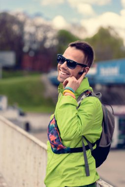 Gülümseyen mutlu turist kulaklık cihazıyla telefonda konuşuyor.