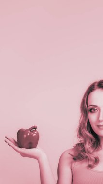 Genç ve güzel bir kadının elinde kırmızı biber, pembe renkli monokrom görüntüsü.