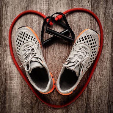 Kalp şeklinde spor ayakkabılar ve kırmızı direniş bandı izole edilmiş.