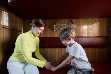 Anne ve oğlu tren kompartımanında oturup oynuyorlar.