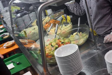 Kafedeki yemek kuyruğundaki farklı yemeklerin yakın plan fotoğrafı.