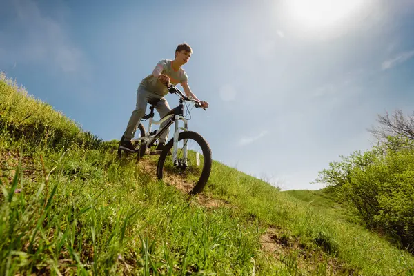 Dnepr, Ukrayna - 21 Nisan 2018: Çimenli tepede bisiklete binen genç erkek bisikletçi