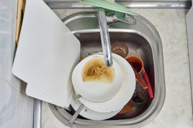 Mutfak lavabosunda bir yığın kirli bulaşık var.