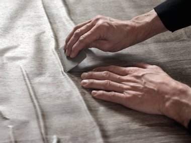 Marangozların elleri birbirine yapışkan filmden havayı temizliyor.