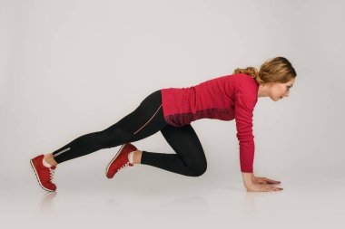 Gri arka planda izole edilmiş şınav çeken güçlü genç kız.