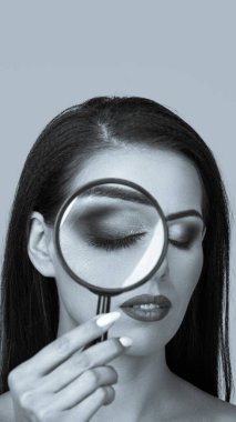 Genç ve güzel bir kadın büyüteçten bakıyor. hikaye kullanımında kullanışlı görünüm oranı. mavi renkli tek renkli siyah beyaz resim.