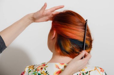 Kızıl kısa müşterilerin saçlarını tarayan kuaför elleri