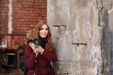 Gülümseyen mutlu kadın dijital kamerayla dışarıda fotoğraf çekiyor.