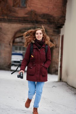 Kış caddesinde yürüyen mutlu kadın fotoğrafçı.