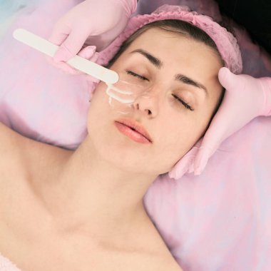 Kuaförde kadın yüzüne yaşlanma karşıtı maske takan bir kozmetikçi.