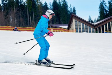 Genç aktif kadın kış dağlarında kayak yapıyor.