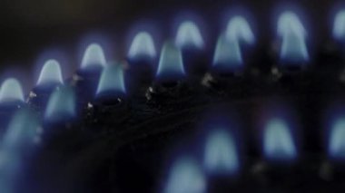 Metal ocağın üzerindeki gaz alevinin sinematik makro görüntüsü. Gaz ocağının mavi alevlerle tutuşan makro görüntüsü. Gaz sobasının titreşen alevinin detaylı makro görüntüleri. Mutfak gaz sobasının yakın çekimi ısı dalgalarıyla tutuşuyor.