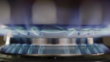 Metal ocağın üzerindeki gaz alevinin sinematik makro görüntüsü. Gaz ocağının mavi alevlerle tutuşan makro görüntüsü. Gaz sobasının titreşen alevinin detaylı makro görüntüleri. Mutfak gaz sobasının yakın çekimi ısı dalgalarıyla tutuşuyor.