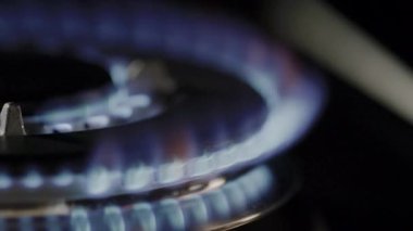 Metal ocağın üzerindeki gaz alevinin sinematik makro görüntüsü. Gaz ocağının mavi alevlerle tutuşan makro görüntüsü. Gaz sobasının titreşen alevinin detaylı makro görüntüleri. Mutfak gaz sobasının yakın çekimi ısı dalgalarıyla tutuşuyor.