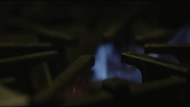 Metal ocağın üzerindeki gaz alevinin sinematik makro görüntüsü. Gaz ocağının mavi alevlerle tutuşan makro görüntüsü. Gaz sobasının titreşen alevinin detaylı makro görüntüleri. Mutfak gaz sobasının yakın çekimi ısı dalgalarıyla tutuşuyor.
