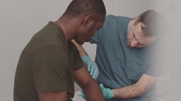 Střední Zpomalení Bělošského Armádního Lékaře Vyšetřujícího Zraněnou Ruku Afroamerického Vojáka — Stock video