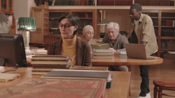 Средняя Медлительность Взрослой Женщины Библиотекаря Очках Сортирует Классифицирует Книги Рабочем — стоковое видео