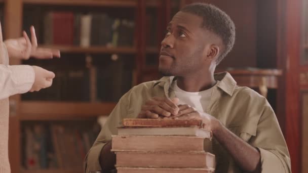 Tilt Slowmo Smiling Young Black Man Disability Sitting Pile Books — Stockvideo