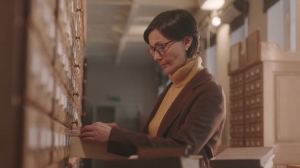 Medium Side View Mature Female Librarian Eyeglasses Sorting Classifying Library — Stockvideo
