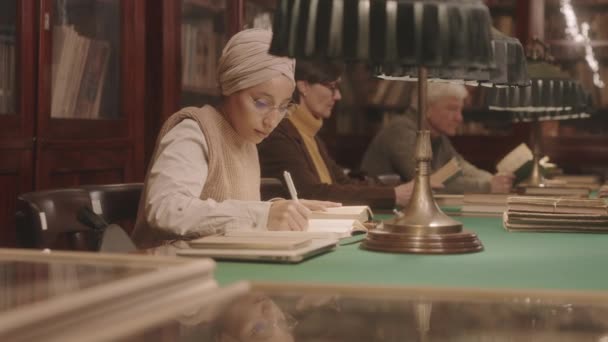 Medium Slowmo Muslim Female University Student Taking Notes Copybook While — Vídeo de Stock