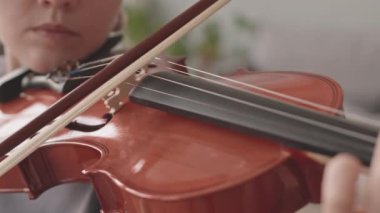 Evde keman çalan yetenekli beyaz kadının yavaş yavaş yakın çekimi, ön plandaki müzik aletine odaklan.