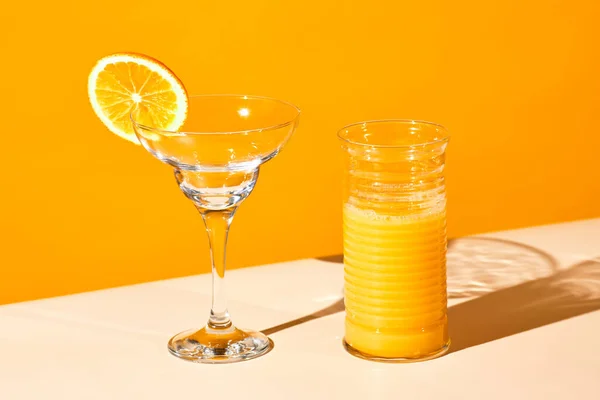 stock image Vibrant still life of orange juice and water glass against colored background, copy space