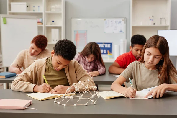 Okul Sınıfındaki Masalarda Planda Kimya Modeliyle Çalışan Çeşitli Çocukların Manzara — Stok fotoğraf
