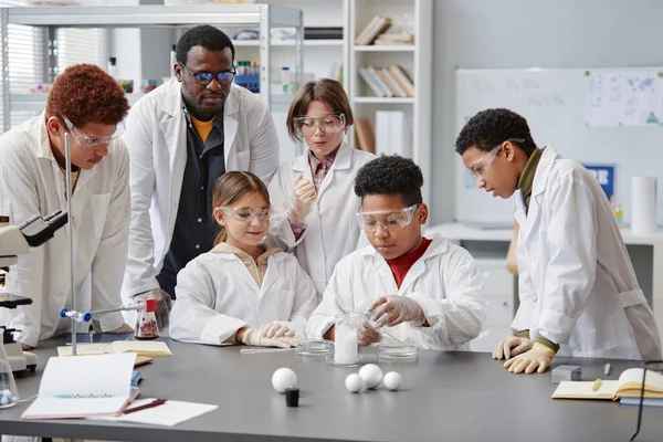 Diverse group of children wearing lab coats in chemistry class while enjoying science experiments