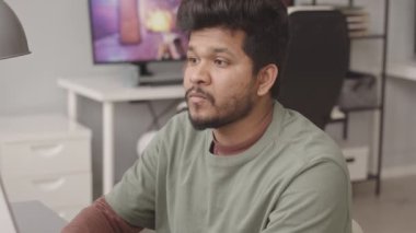 Modern ofiste masa başında oturmuş bilgisayar oyunu geliştiren iki ırklı genç adamın belini kaldır.