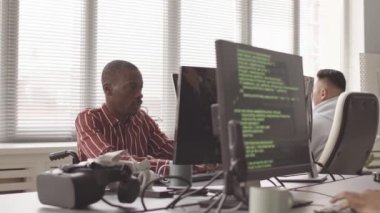 Modern açık uzay ofisinde birlikte çalışırken bilgisayarlarında program kodları yazan çeşitli yazılım geliştiricilerinin yavaş belini kaldır