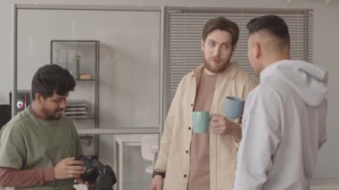 Modern ofiste kahve molası sırasında sohbet eden çeşitli video oyunları geliştiricilerinden oluşan orta yavaş bir ekip. Adamlardan biri elinde siyah bir vr kulaklık tutuyor.