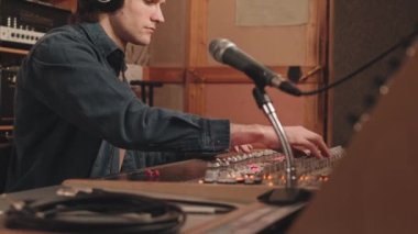 Profesyonel müzik stüdyosunda yeni şarkıcılar kaydedilirken miksaj tahtası kullanan konsantre müzik yapımcısının belini kaldır.
