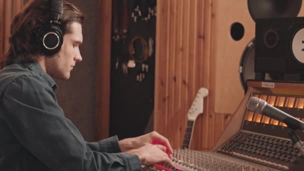 Kulaklıklı Beyaz Erkek Müzik Yapımcısının Belini Kaldır Profesyonel Stüdyoda Masasında — Stok video