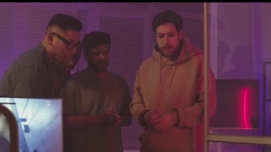 Karanlık ofiste neon ışıkla birlikte çalışan çok ırklı video oyunu geliştiricilerinin orta yavaşlaması, yeni fps oyunu yaratıyor