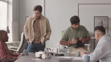 VR oyun geliştirmeyi tartışan çeşitli programcılardan oluşan orta yavaş bir ekip modern ofiste masada oturuyor.