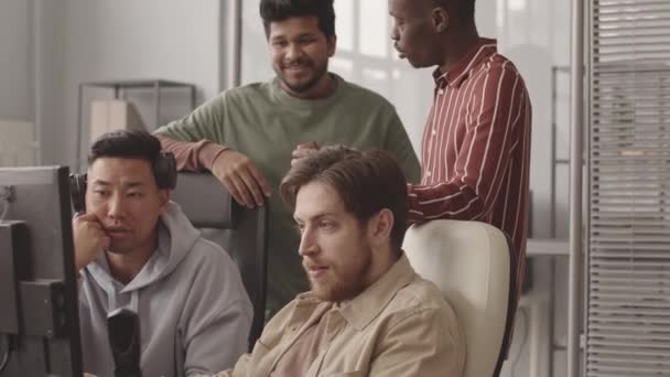 現代のオフィスで同僚ながら コンピュータモニターを見て 会話を持つ4人の男性プログラマーの多民族チームの中低速 — ストック動画