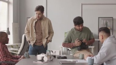 VR oyun geliştirmeyi tartışan çeşitli programcılardan oluşan orta yavaş bir ekip modern ofiste masada oturuyor.