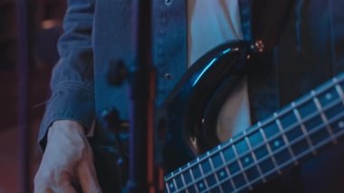Kameraya bakan, bas gitar çalan, mikrofonda şarkı söyleyen, konserde yeni bir şarkı söyleyen Kafkasyalı genç adamın yavaş yavaş yakın çekimini yapın.