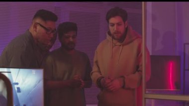 Karanlık ofiste neon ışıkla birlikte çalışan çok ırklı video oyunu geliştiricilerinin orta yavaşlaması, yeni fps oyunu yaratıyor