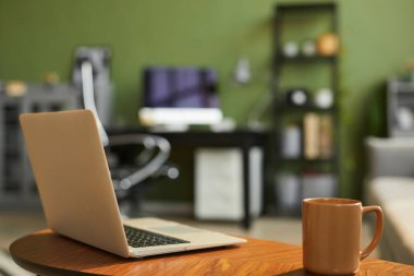 Konforlu oturma odasındaki açık dizüstü bilgisayarın ve kahve fincanının arkaplan görüntüsü, boşluğu kopyala