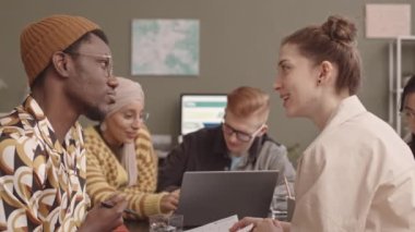 İş stratejisi ve ofis masasında rahat ve gayri resmi bir ortamda oturan beyin fırtınası fikirleri üzerinde çalışan çeşitli yaratıcı genç ekibin orta yavaşlığı.