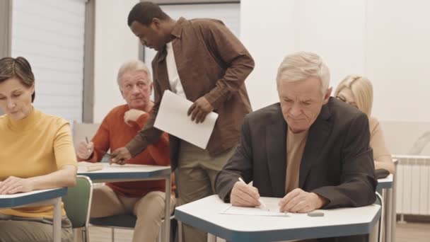 Medium Slowmo Male Black Teacher Walking Desks While Helping Group — Stock video