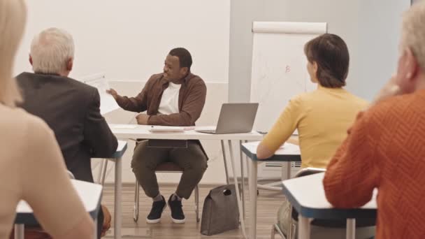 Медленно Черного Учителя Бумажными Тестами Математике Руках Сидящего Столом Современном — стоковое видео