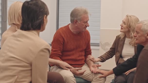 大人の男性と女性のグループの減速グループ治療セッション中に彼の問題を共有し 落ち込んでシニア男性を聞いてサポートします — ストック動画