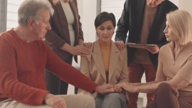 Yavaş yavaş ağlayan beyaz kadın ve diğer grup terapi üyeleri onu destekliyor, duygusal yardım ve bakım sağlıyorlar.