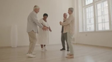 Ayna eşliğinde geniş dans stüdyosunda dans eden gündelik giyimli dört farklı son sınıf öğrencisinin tam boy çekimi.