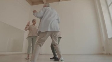 Parlak ferah dans stüdyosunda iki enerjik son sınıf öğrencisi ve kadının birlikte dans edişinin arkası.