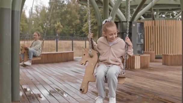 Slowmo Dvou Desetiletých Bělošek Užívá Houpání Dřevěných Koňské Houpačce Hřišti — Stock video
