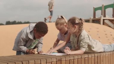 Okul arkadaşlarının yavaş yavaş tebeşirle çizdiği yaz tatillerini oyun sahasında geçirirken