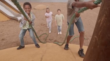 Yaz mevsiminde çocuk parkında duvara tırmanırken çeşitli öğrencilerin ip kullandıkları yüksek açılı bir çekim.